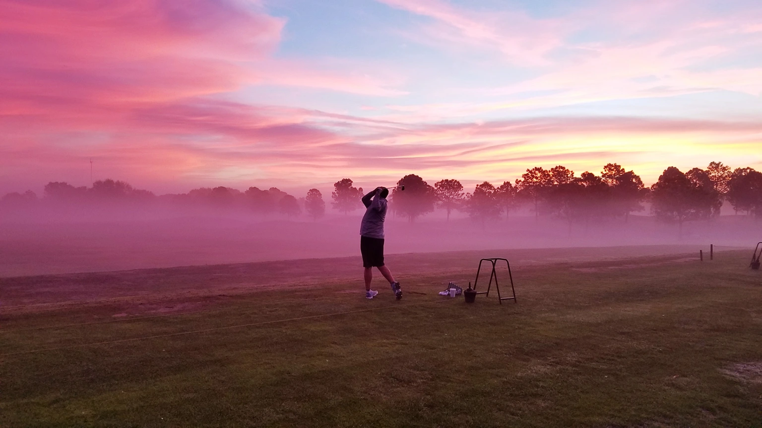 Golfer practicing swing at sunrise